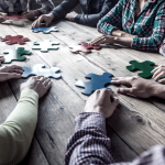 Équipe assemblant des pièces de casse-tête autour d’une table