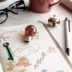 Carnet d’idées avec dessins, ampoule et crayon sur un bureau