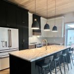 Cuisine sur mesure avec armoires noires et blanches et grand îlot central