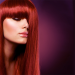 Portrait d’une femme aux longs cheveux roux lisses, avec une frange droite.