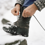 Personne attachant une botte d’hiver dans la neige