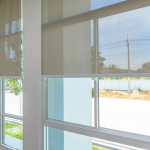 Grandes fenêtres à cadres blancs avec des stores partiellement abaissés.
