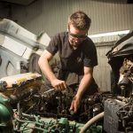 Mécanicien travaillant sur le moteur ouvert d’un camion dans un atelier.