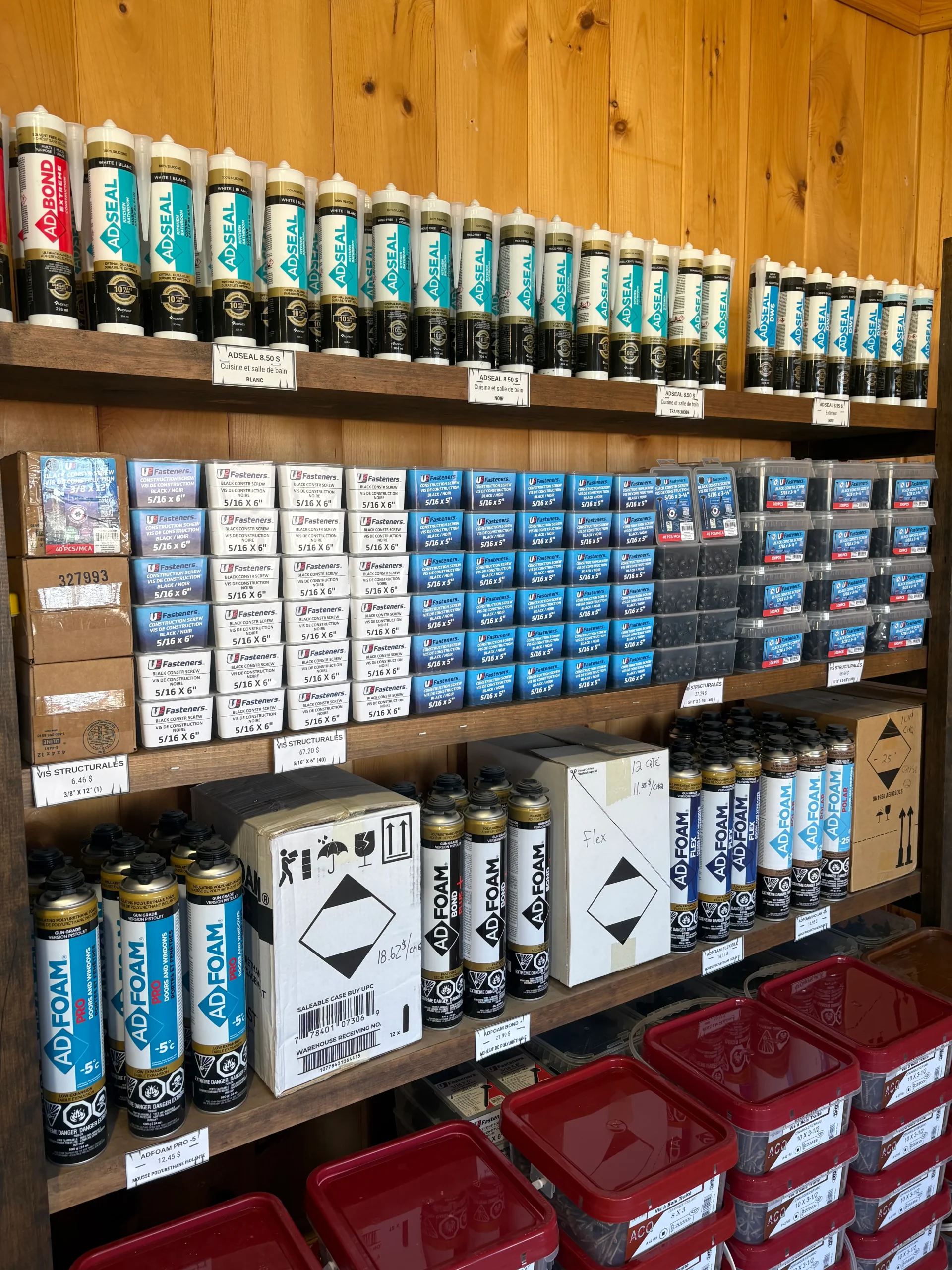 Présentoir de fournitures pour le travail du bois chez Fran-Lou, comprenant vis, silicones, adhésifs et produits de finition soigneusement sélectionnés.